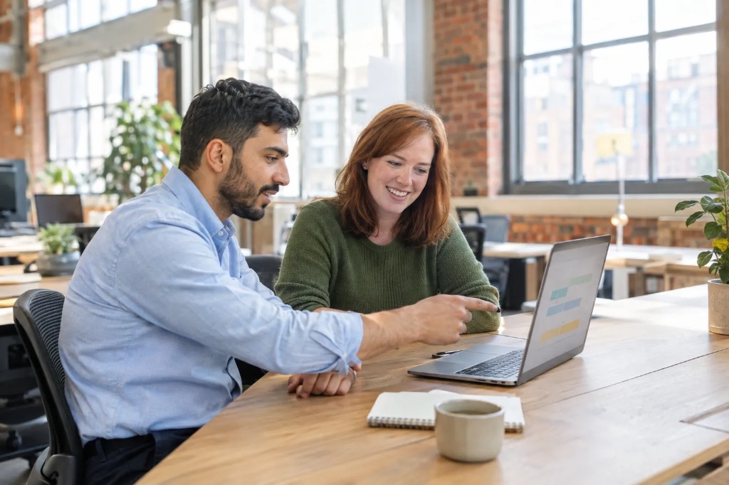 Business management graduate reviewing a project plan with a colleague in a Birmingham office.